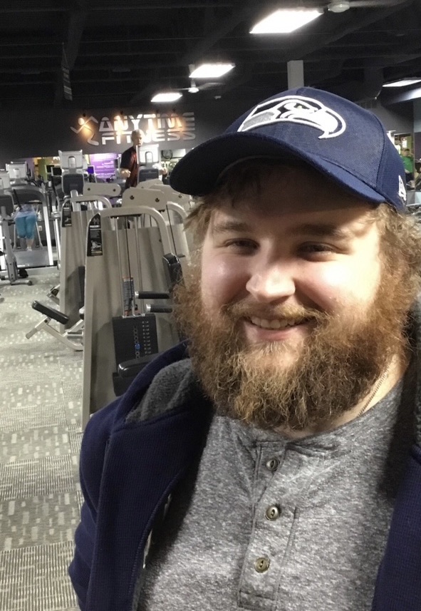 Brian at around 25 in a gym, bearded, in a baseball cap, at his heaviest